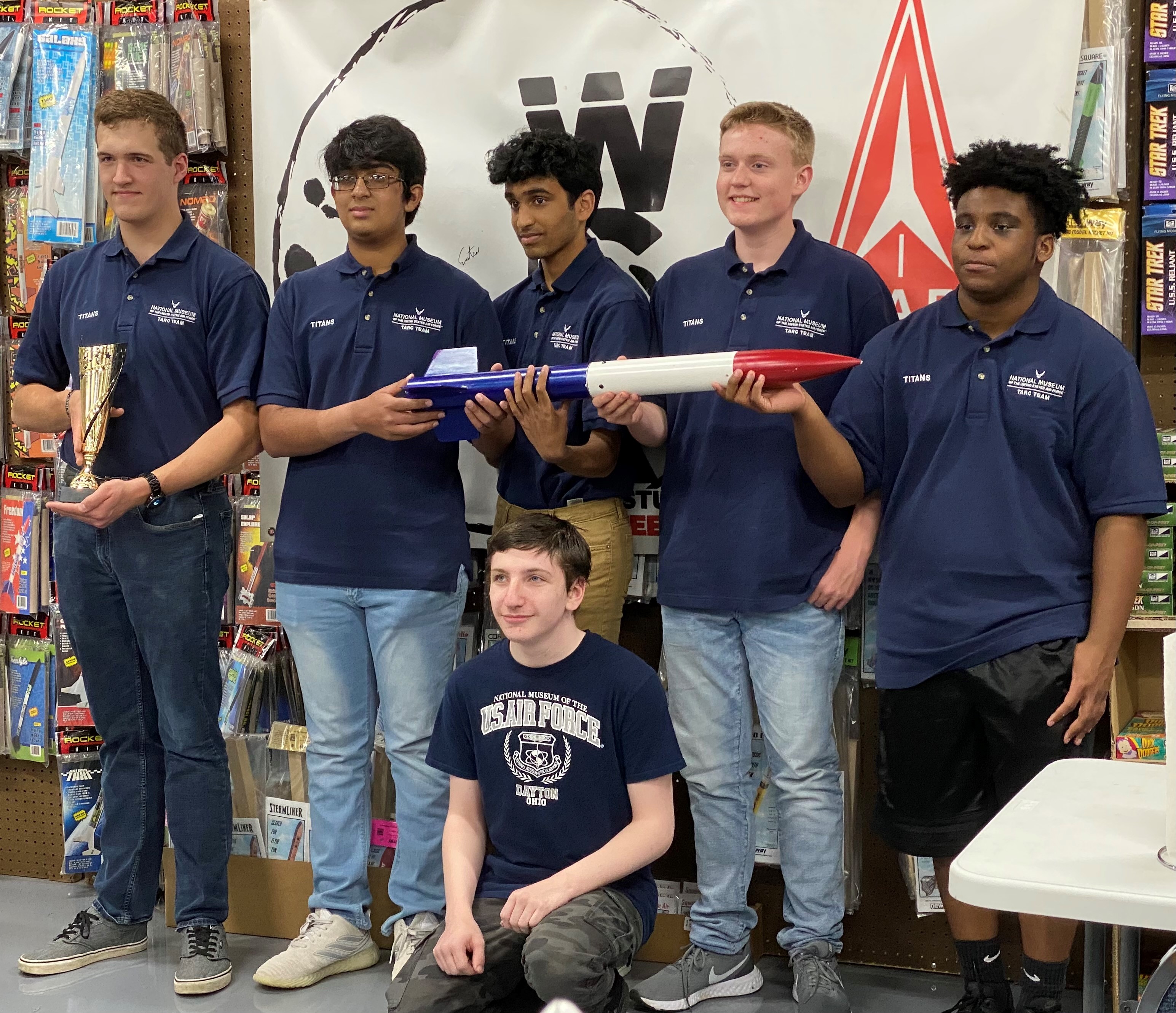 Picture of 6 young men holding a model rocket and a trophy