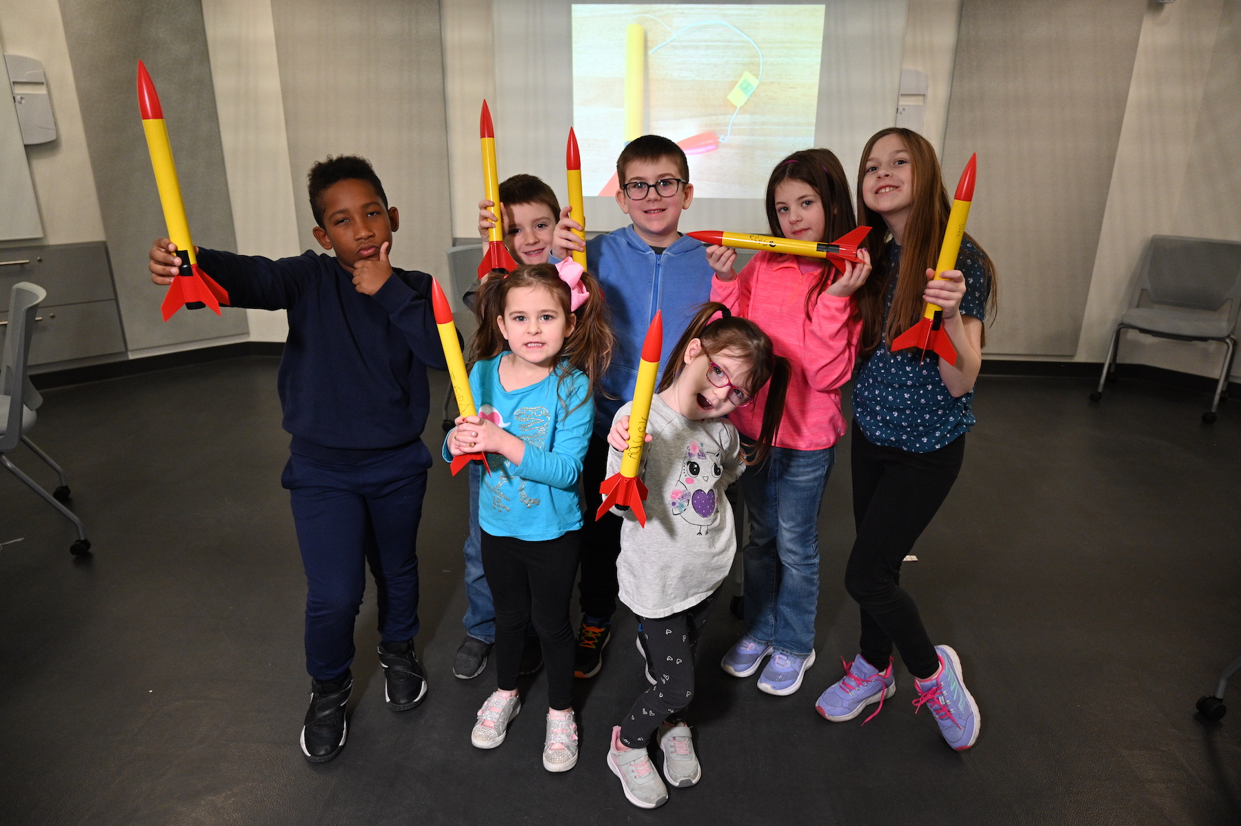 image of a group of young students who have just built model rockets. they are standing together holding up their rockets that are red and yellow.