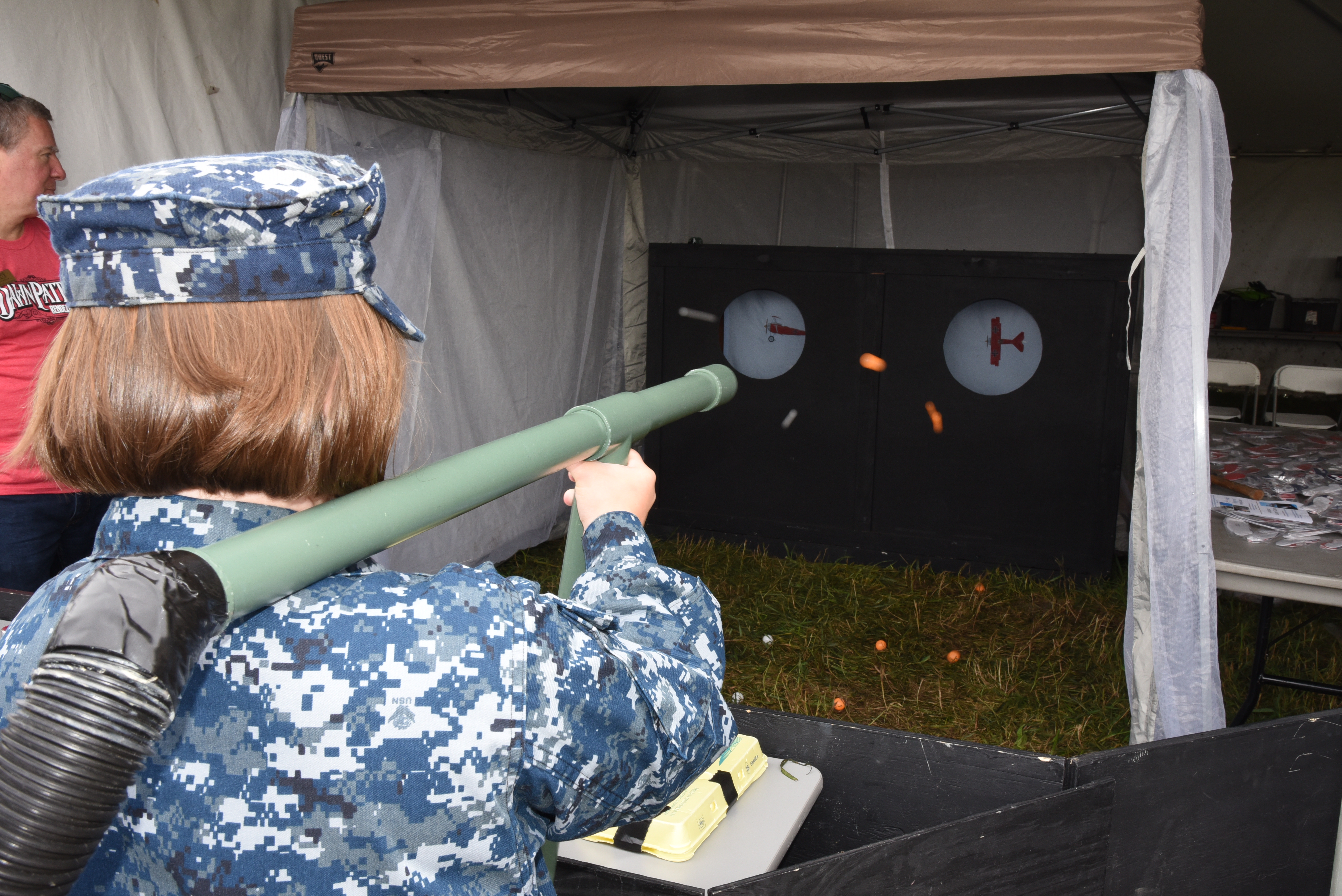 Image of a person in a navy uniform shooting the bernouli cannon game at a target