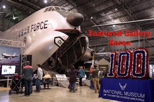 Image of the Korean War Gallery entrance with a table and the number 100 flower display in front of the C-182